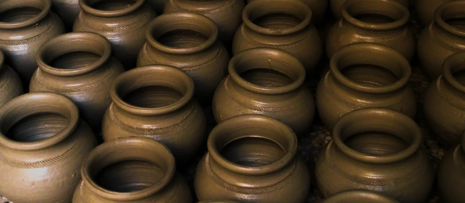 Rows and rows of identical unfired clay pots, waiting in a workshop.